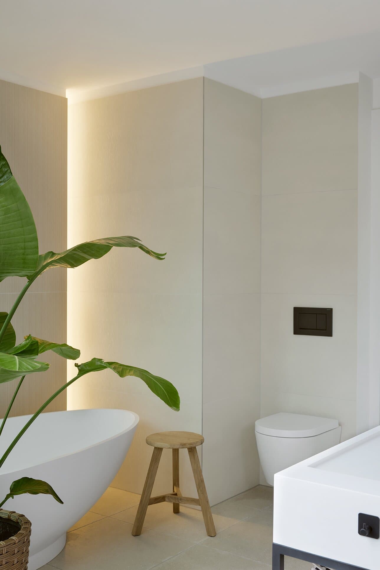 Atmospheric detail shot of the master bathroom with cove lighting and a teak stool