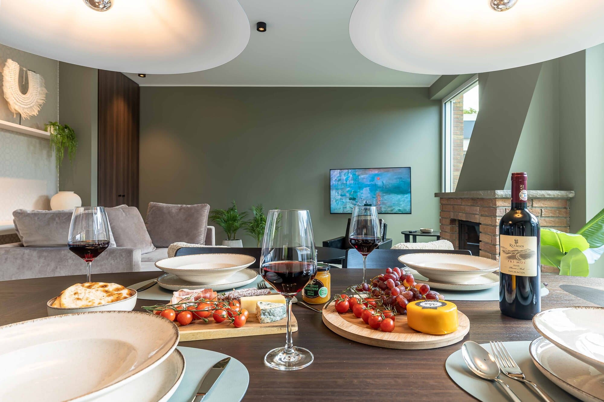Dining table set with wine, cheese and bread, looking through the open living area