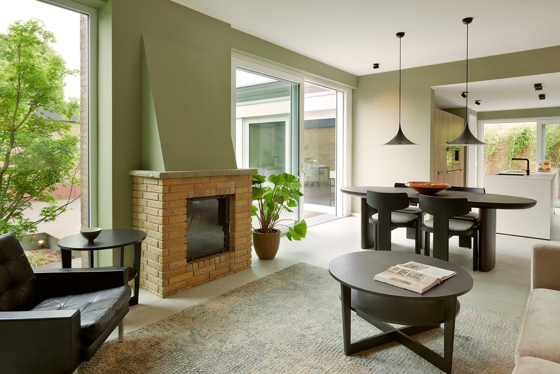 Wohnzimmer mit beigem Sofa, Klinker-Akzentwand und offener Verbindung zur Küche