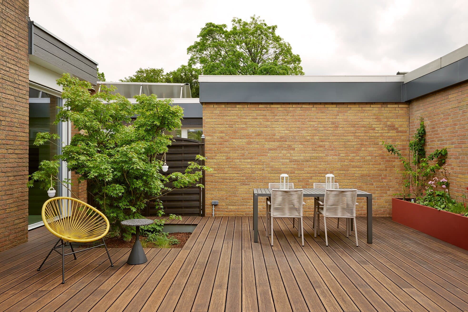 Innenhof 1 bei Tageslicht mit gelbem Acapulco-Sessel, Beistelltisch und Outdoor-Esstisch